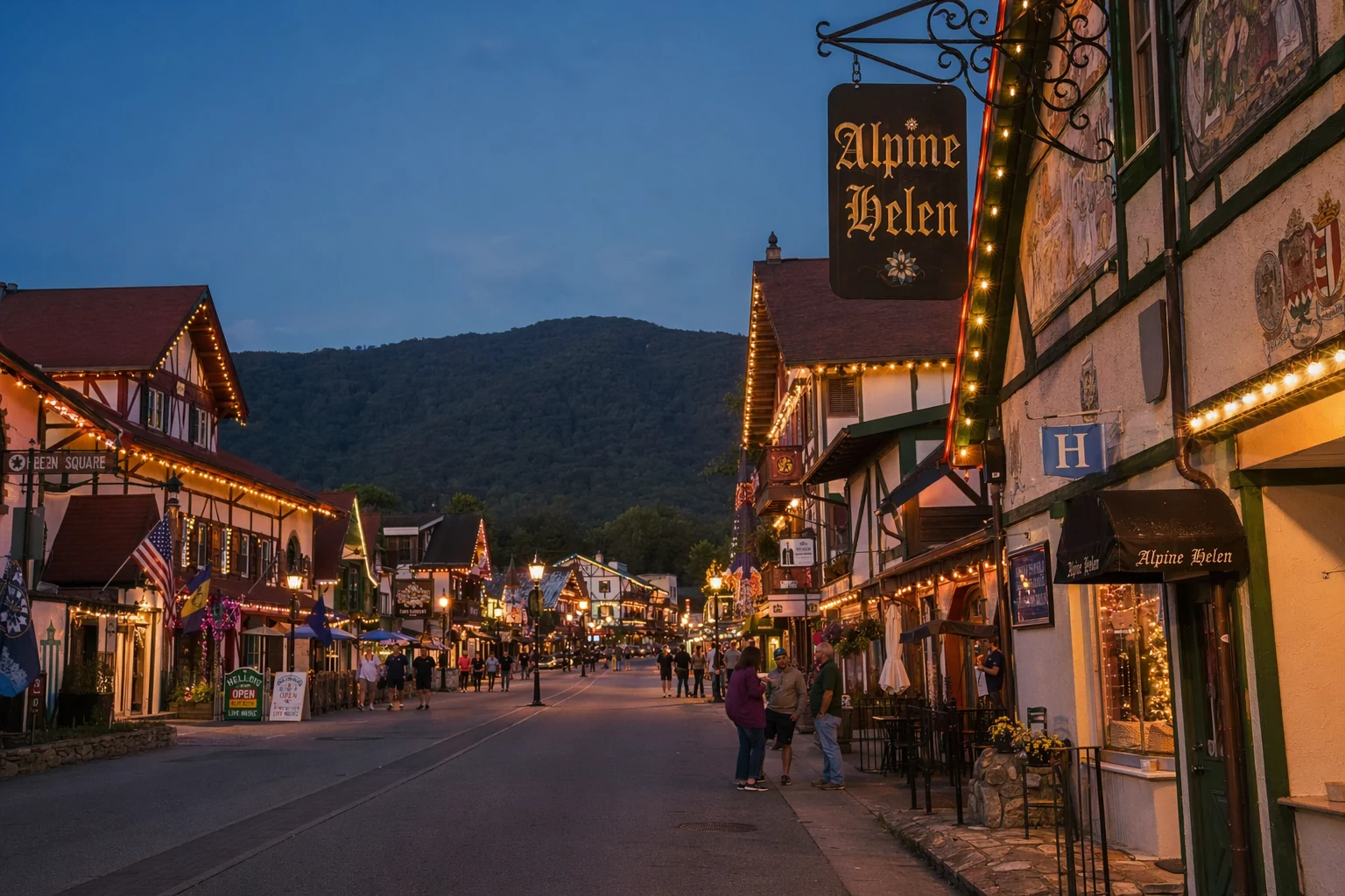 Main Street in Helen, Georgia at dusk, with Bavarian-style buildings lining both sides of the road. String lights glow warm yellow along the storefronts, illuminating hand-painted murals and timber-frame facades painted in cream, burgundy, and forest green. Restaurant signs in Gothic lettering hang from wrought iron brackets. The street is wide and paved, with a few visitors strolling between shops. Mountains rise dark in the background under a deep blue twilight sky. This recreated alpine village atmosphere showcases the unique architectural theme that defines Helen's dining and shopping district, all concentrated within a few walkable blocks along the Chattahoochee River.