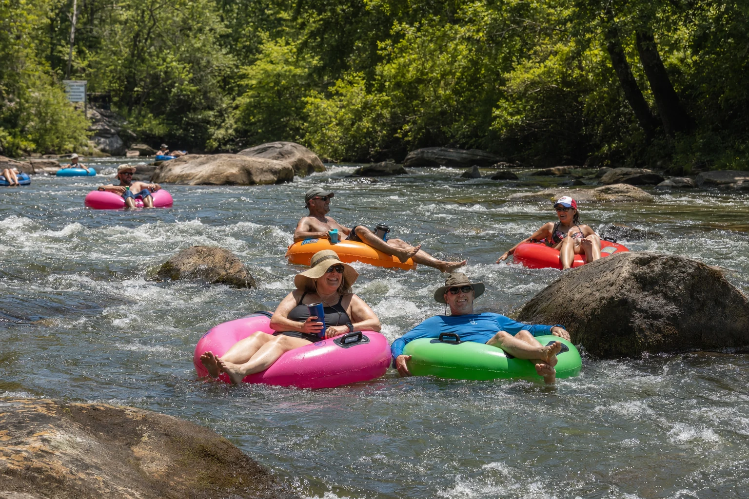 Friends floating down the rocky Chattahoochee River on colorful inner tubes